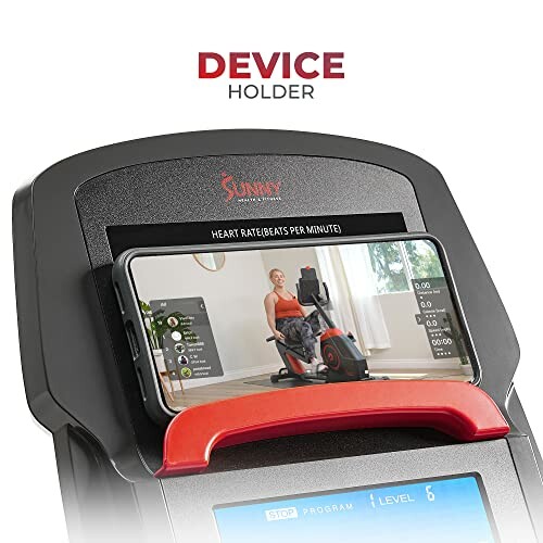 Exercise bike with device holder displaying a workout video.