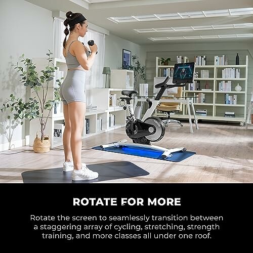 Person exercising in a home gym with a rotating screen bike and yoga mat.